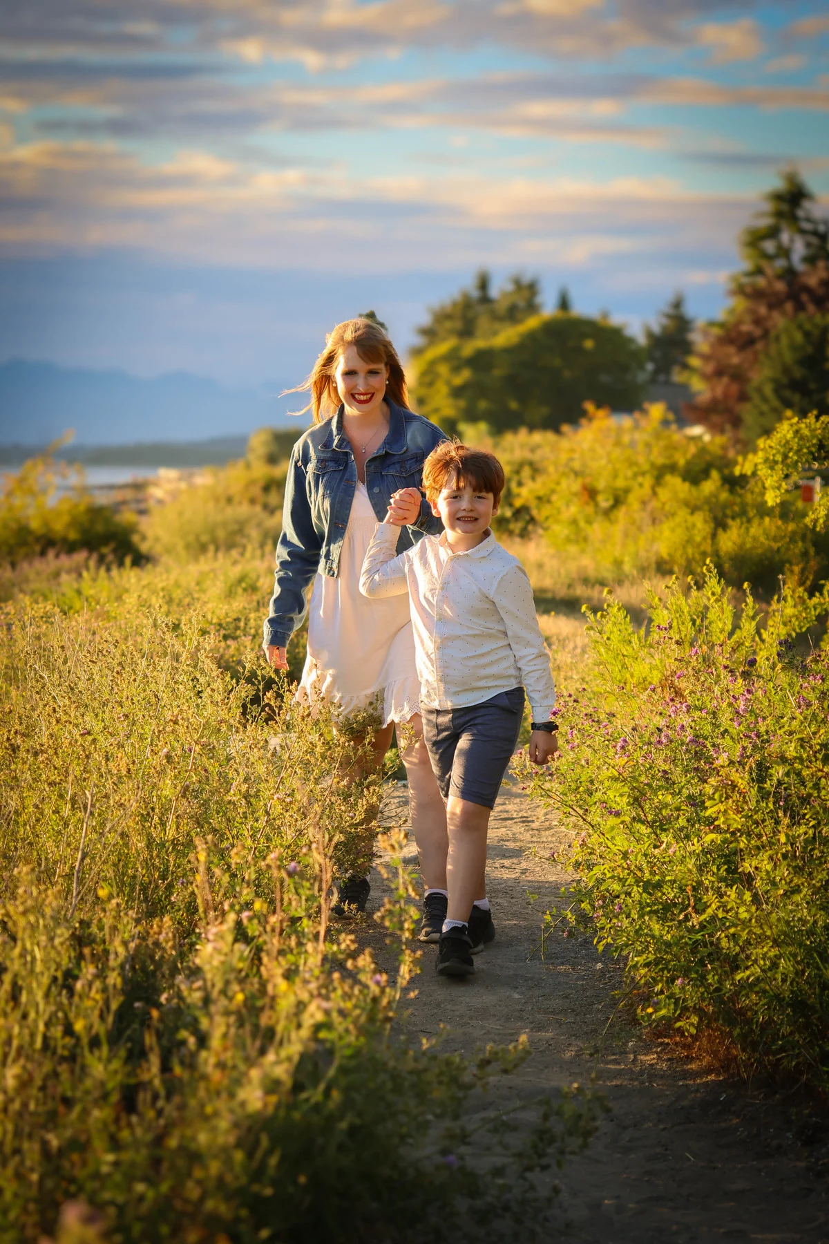 A mother and child walking hand in hand through warm evening light